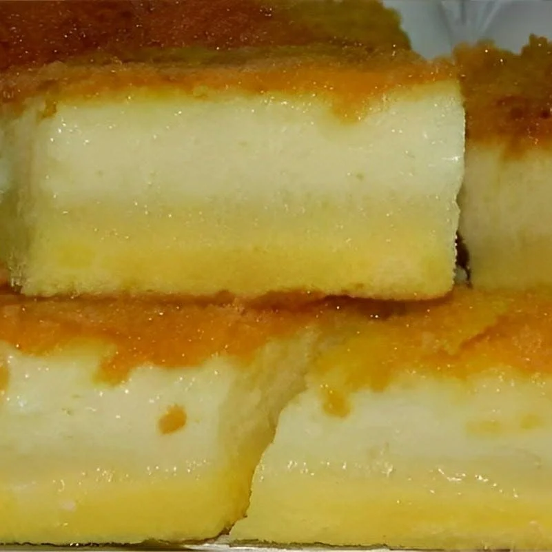 Bolo de fubá cremoso com queijo cortado ao meio, mostrando interior úmido semelhante a pudim