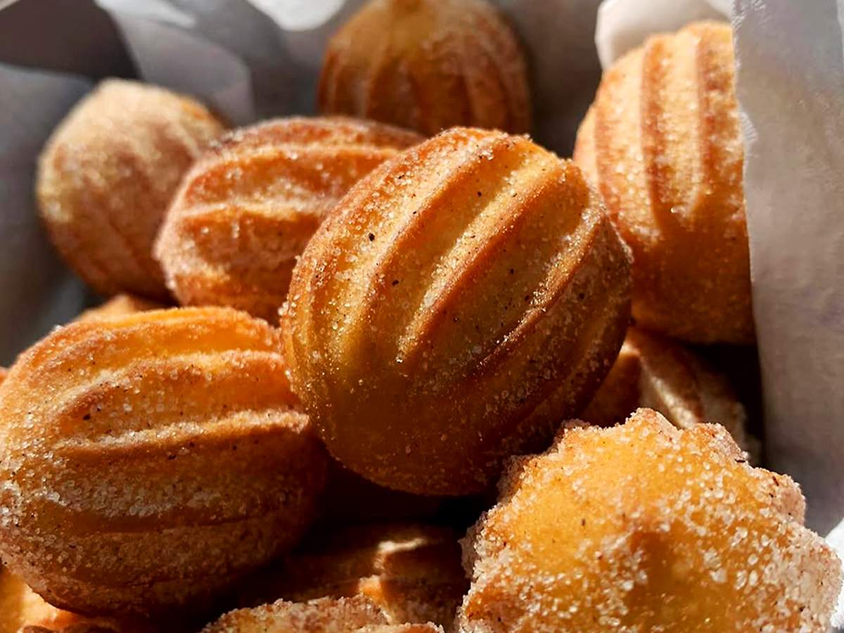 Churros caseiros crocantes em prato com açúcar e canela, ao lado de doce de leite